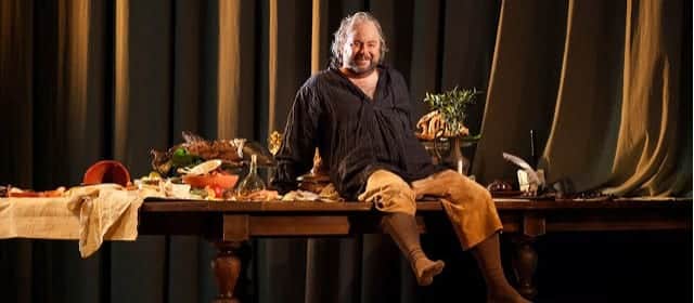 falstaff reclines on a table loaded with food