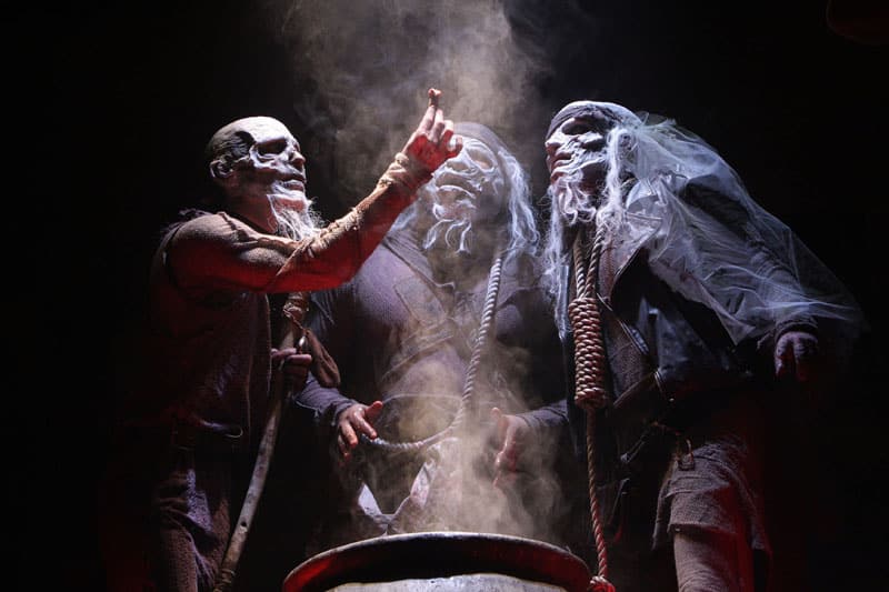 Three witches around a cauldron. These witches are possibly the cause of the curse on the play, which is an answer to one of our questions about Shakespeare.